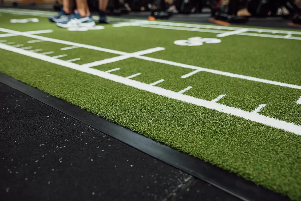 Close-up of a green Heroturfs sled track with white markings in a gym