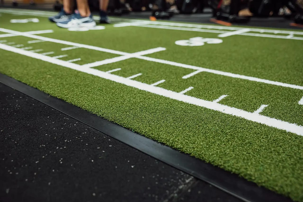 Close-up of a green Heroturfs sled track with white markings in a gym